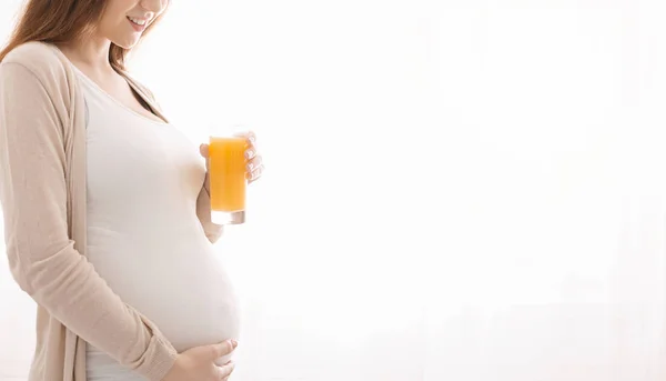Wanita hamil memegang kaca dengan jus jeruk — Stok Foto