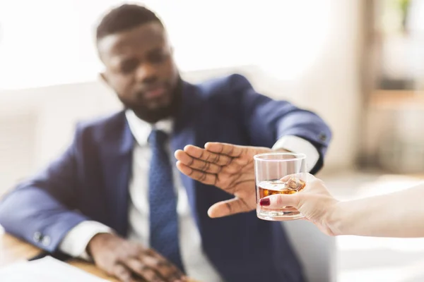 Businessman saying no to glass of whiskey offered by colleague