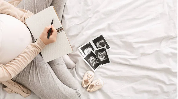 Schwangere notiert Gedanken im Bett — Stockfoto