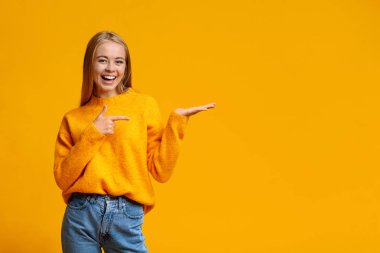 Neşeli genç kız boş avucunda bir şeyler gösteriyor.