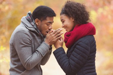Parkta nefesini ısıtan kadın elleri olan adam.