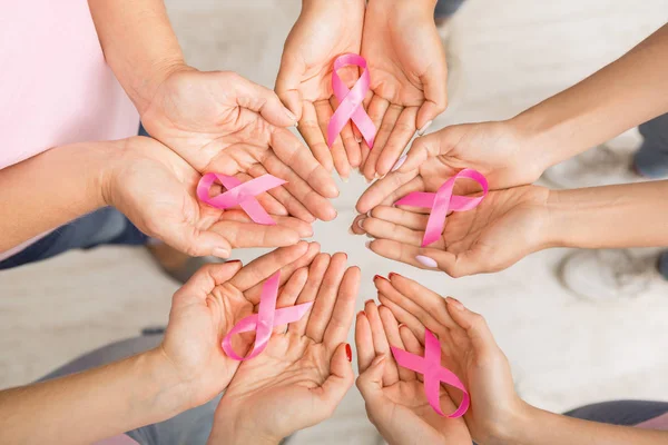 Círculo de manos de las mujeres sosteniendo cintas de cáncer de mama rosa, fondo blanco — Foto de Stock