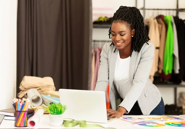 Afro-Amerikaanse naaister met behulp van laptop werken in de showroom — Stockfoto
