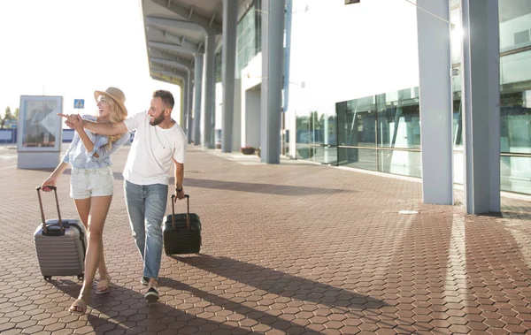 Coppia felice che arriva in aeroporto, tirando valigie all'aperto — Foto Stock