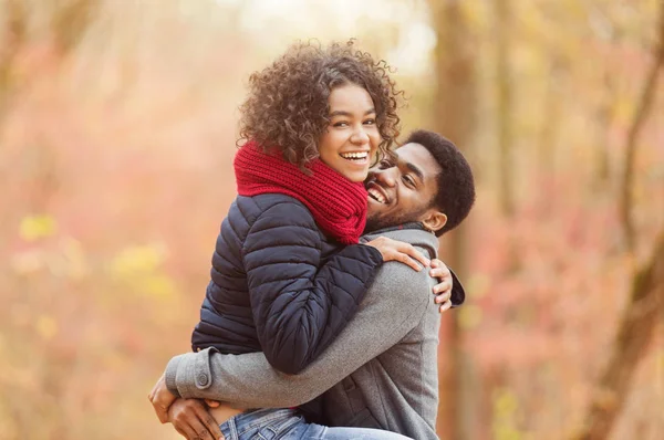 Emocionada pareja afro disfrutando de momentos de felicidad en el parque de otoño —  Fotos de Stock