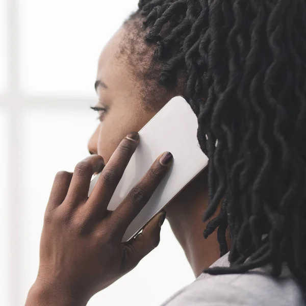 Afro Affärskvinna talar på mobiltelefon tittar ut genom fönstret, närbild — Stockfoto