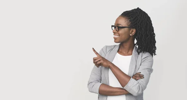 Glimlachende zwarte zakenvrouw wijzend vinger op kopieerruimte, witte achtergrond — Stockfoto