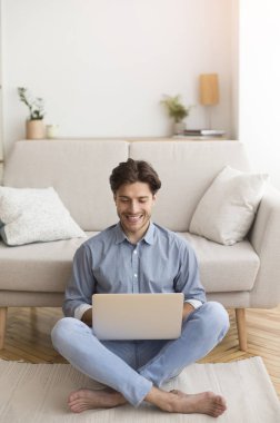 Dizüstü bilgisayarda çalışan serbest çalışan adam içeride oturuyor.