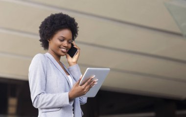 Akıllı telefonu ve tableti olan mutlu bir iş kadını..
