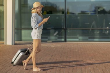 Havaalanında bavulla yürüyen genç bir kız.