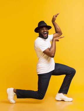 Sarı arka planda Mısır tarzı dans eden komik Afrikalı adam.