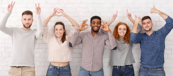 Amis montrant divers signes sur le mur de briques blanches — Photo