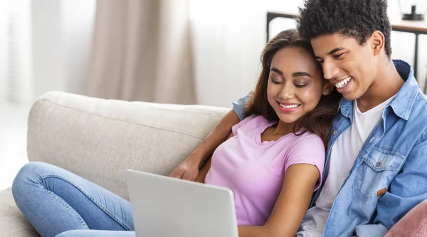 Uśmiechnięta Afrykańska para nastolatków relaksująca i oglądająca film na laptopie — Zdjęcie stockowe