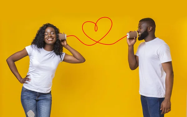 Jong zwart paar met kan telefoon op gele achtergrond — Stockfoto