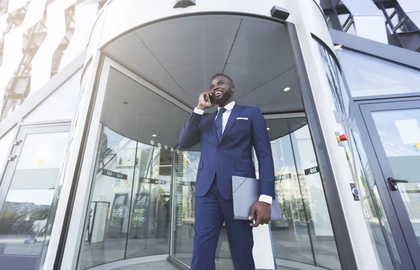 Afro Businessman talar på mobiltelefon mot entré till kontorsbyggnad — Stockfoto