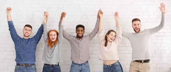 Amigos comemorando o sucesso com as mãos levantadas sobre a parede branca — Fotografia de Stock