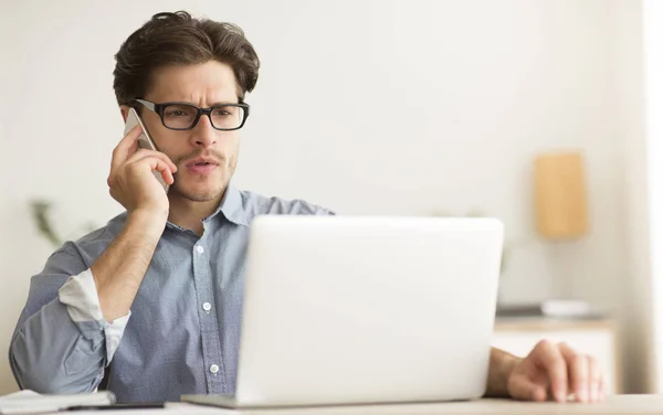 Allvarlig kille pratar på mobiltelefon arbetar på laptop i Office — Stockfoto