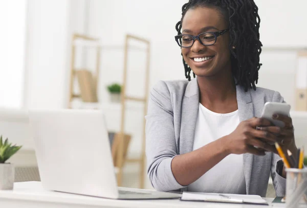 Africano menina de negócios americana mensagens de texto no telefone no local de trabalho — Fotografia de Stock