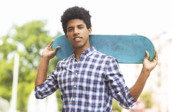 Guapo africano adolescente posando con moderno monopatín en las manos — Foto de Stock