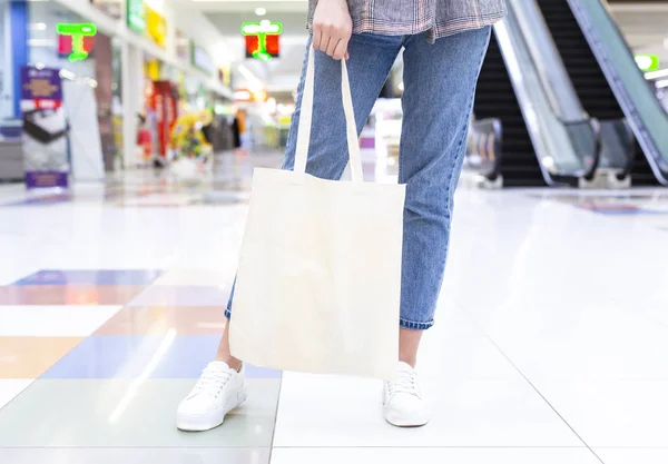 Girl holding blank cotton eco tote bag in shopping center