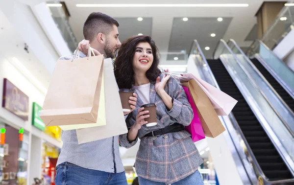 Feliz pareja milenaria descansando en el centro comercial, bebiendo café — Foto de Stock