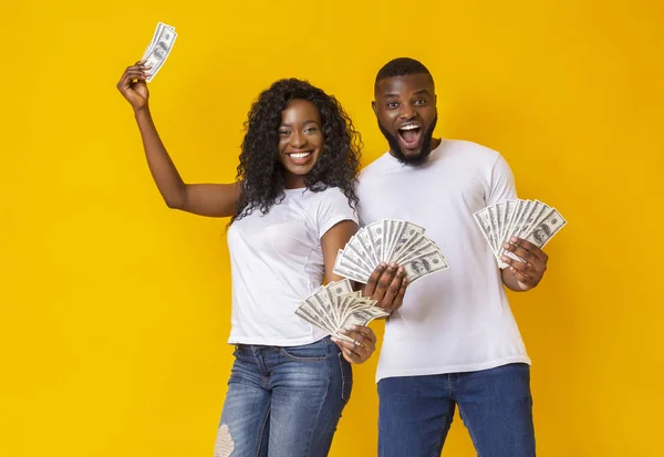 Excited black man and woman holding dollars