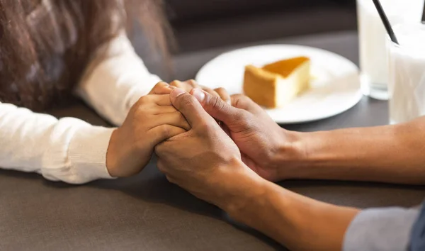 Pareja de carrera mixta cogida de la mano mientras almuerza — Foto de Stock