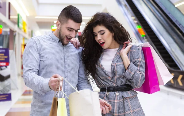 Un par de adictos a las compras. Hombre y mujer mirando en la bolsa de compras —  Fotos de Stock
