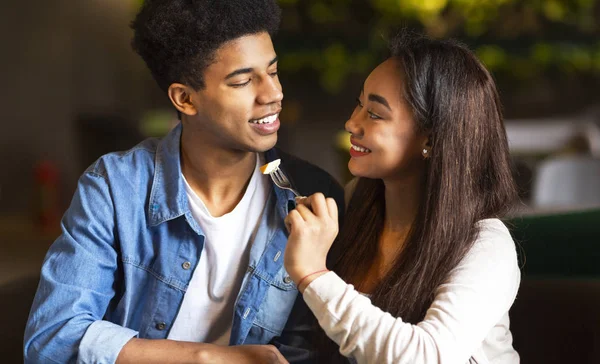 Pretty mixed race teen feeding her boyfriend at cafe