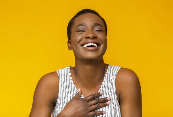 Zabawna afro dziewczyna śmieje się z kamery na żółtym tle — Zdjęcie stockowe