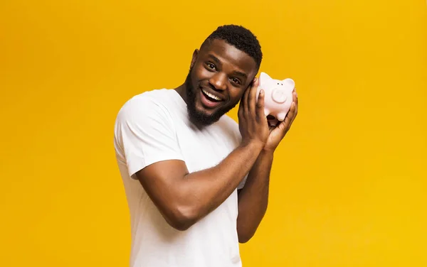 Homem americano africano feliz sacudindo mealheiro completo — Fotografia de Stock