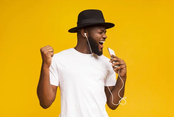 모자를 쓴 행복 한 아프리카 남자 마이크처럼 스마트폰으로 노래하는 모습 — 스톡 사진