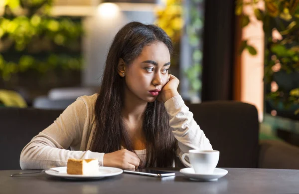 Upset young girl sitting alone at cafeteria — Stock Photo, Image