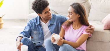 Milenyum çifti ellerinde fincanlarla evde eğleniyorlar.