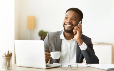 Ofis çalışanı kahve molasında cep telefonuyla konuşuyor.