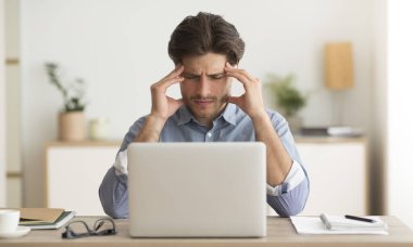 Millennial Guy 'ın baş ağrısı var. Bilgisayarda çalışıyor.