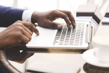 Siyah İşadamı Laptop 'ta daktilo yazıyor, kafede kahve içiyor, yakın plan.