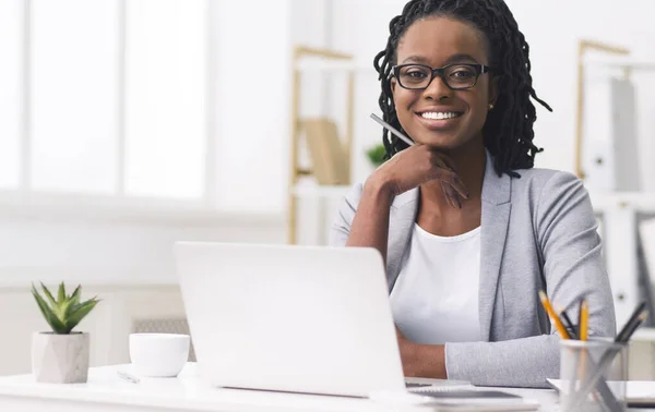 Уверенная афроамериканская предпринимательница улыбается перед камерой на рабочем месте — стоковое фото
