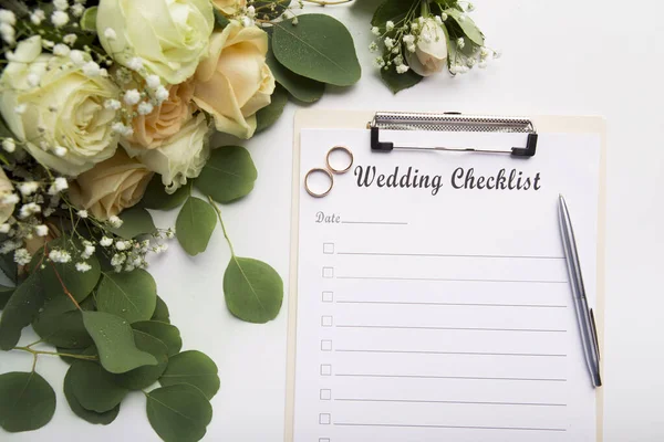 Creative wedding planning checklist with roses and rings