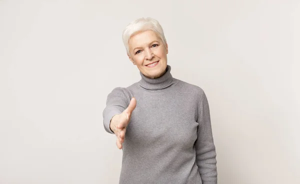Idős nő nyújtja kezét kézfogás a kamera — Stock Fotó