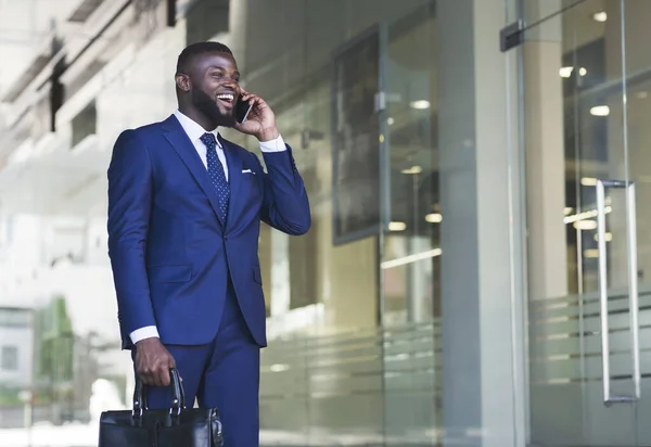 Veselý podnikatel vede telefonickou konverzaci vedle kancelářské budovy — Stock fotografie