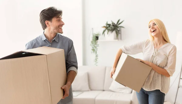 Подружжя сміється і жартує несучи рухомі коробки в новому будинку — стокове фото
