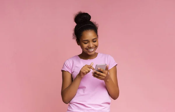 Coolt program. Intresserad flicka Använda smartphone på rosa bakgrund — Stockfoto