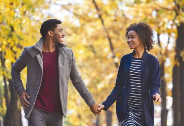 Sonbahar ormanlarında yürürken el ele tutuşan siyah çift