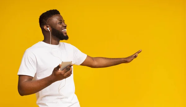 Vrolijke zwarte man luisteren muziek in oortelefoons op smartphone — Stockfoto