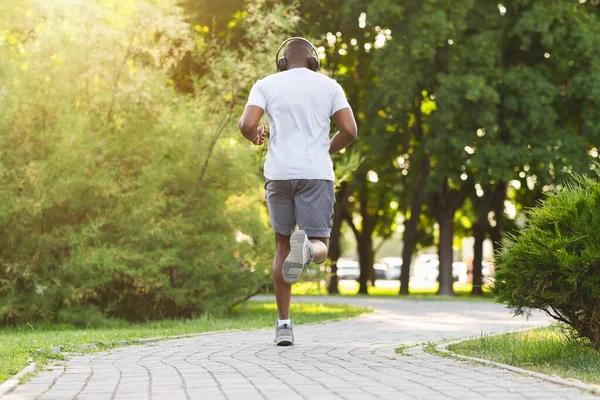 Hombre atlético y negro corriendo a lo largo del sendero del parque —  Fotos de Stock