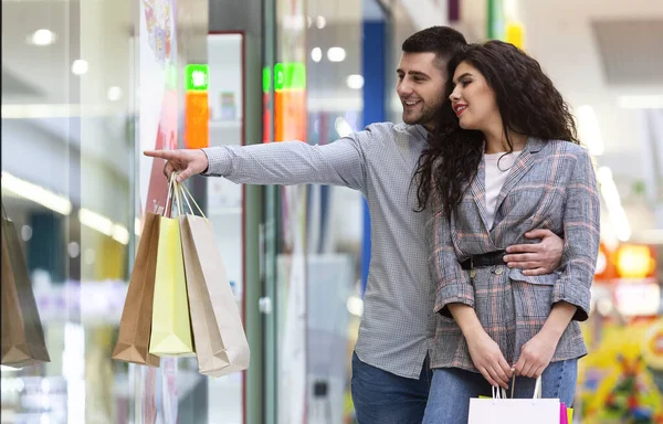Mężczyzna pokazuje coś żonie w witrynie sklepu — Zdjęcie stockowe