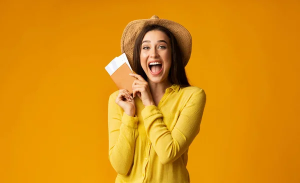 Chica turista feliz sosteniendo boletos y pasaporte sobre fondo amarillo — Foto de Stock