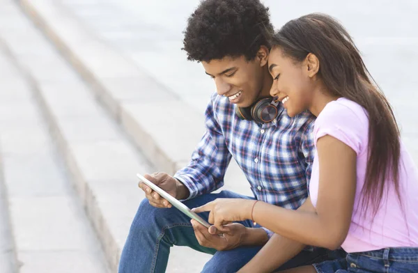 Pareja joven navegando por las redes sociales en tabletas digitales al aire libre —  Fotos de Stock