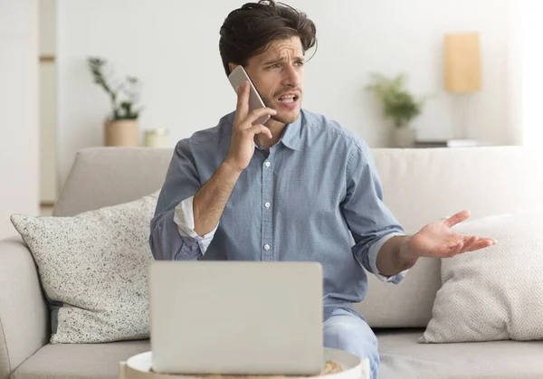 Ontevreden Guy klagen over problemen met laptop via de telefoon Indoor — Stockfoto